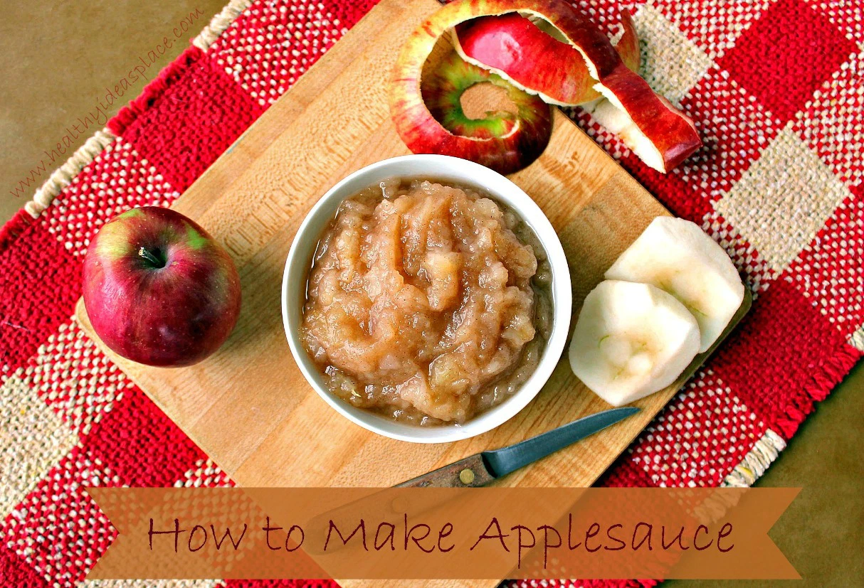 Homemade Chunky Applesauce in a white bowl on a cutting board with apples