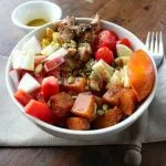 Fall Salad Bowl with Roast Butternut Squash in a white bowl with container of vinaigrette in the background