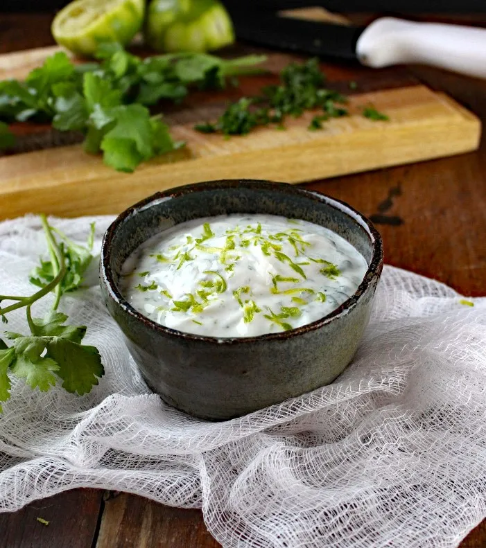 Cilantro Lime Crema in a bowl with ingredients in the background