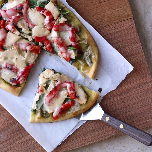 Roasted Red Pepper Chicken and Spinach Naan Pizza close up cut on cutting board