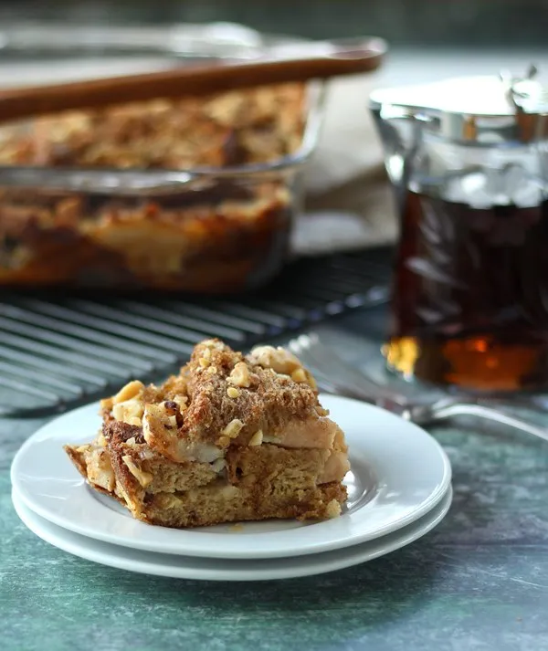 Piece of breakfast casserole on white plate with full pan of it in background