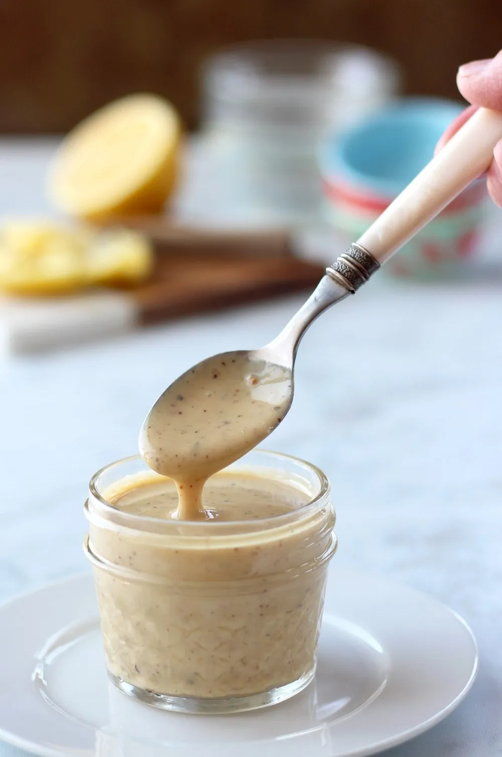 salad dressing in clear jar with cut lemon in background
