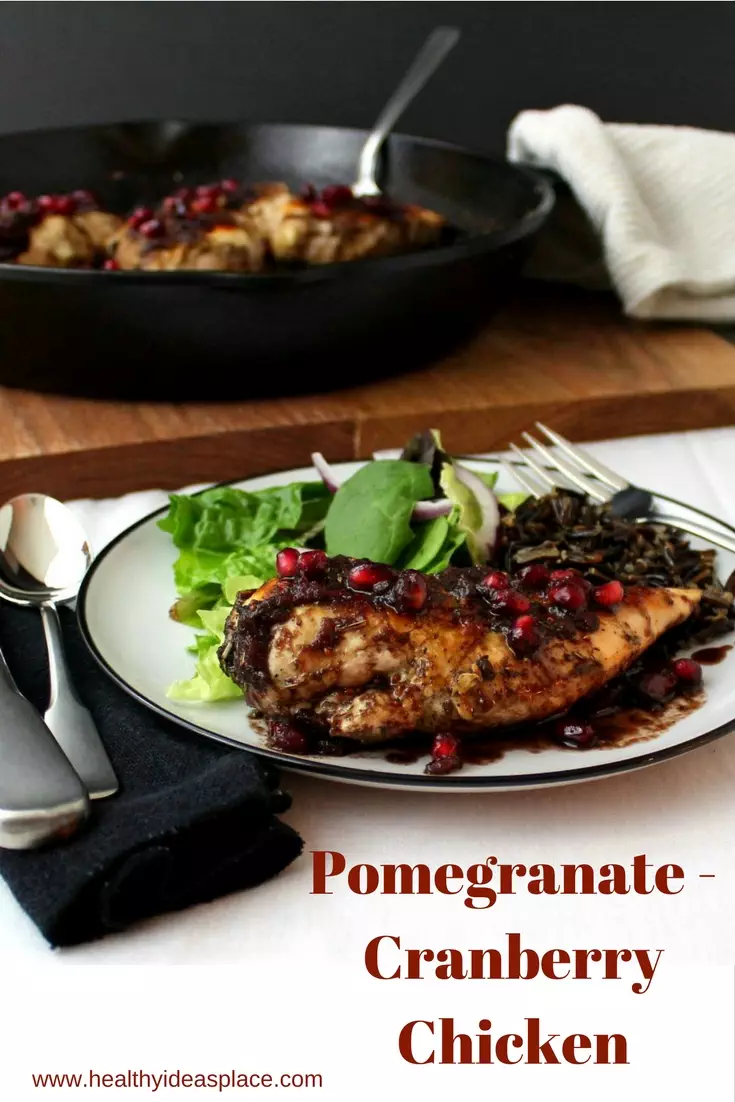Pomegranate-Cranberry Chicken on a plate with a skillet in the background
