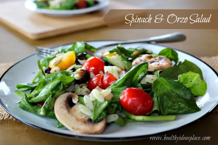 Spinach and Orzo Salad on a white and black plate with a fork