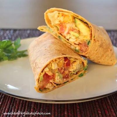 A sliced Tomato & Mango Chicken Salad Wrap on a white plate