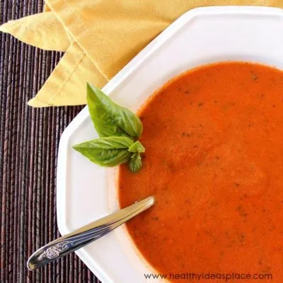 Roasted Tomato Soup in a white bowl with a spring of herbs