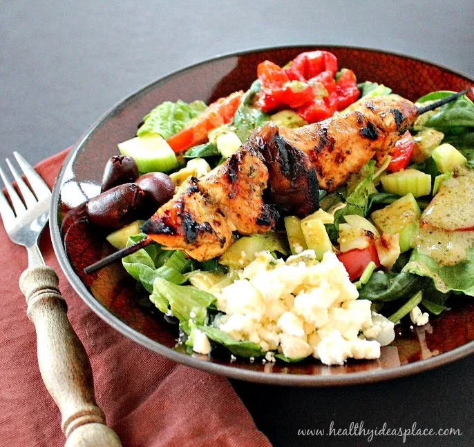 Mediterranean Salad with Grilled Chicken in a bowl with the chicken still on the skewer