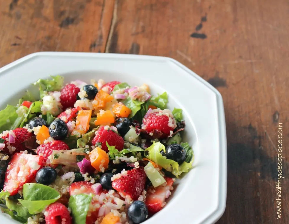 Triple Berry and Quinoa Salad with Mixed Greens places sweet berries and nutty quinoa amidst a backdrop of earthy mixed greens, cucumbers, and peppers, all pulled together with a balsamic vinaigrette for a colorful and scrumptious salad.