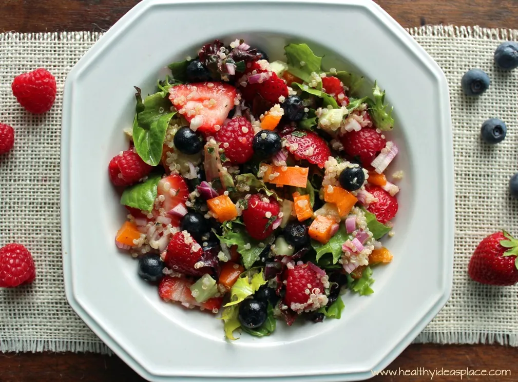 Triple Berry and Quinoa Salad with Mixed Greens places sweet berries and nutty quinoa amidst a backdrop of earthy mixed greens, cucumbers, and peppers, all pulled together with a balsamic vinaigrette for a colorful and scrumptious salad.