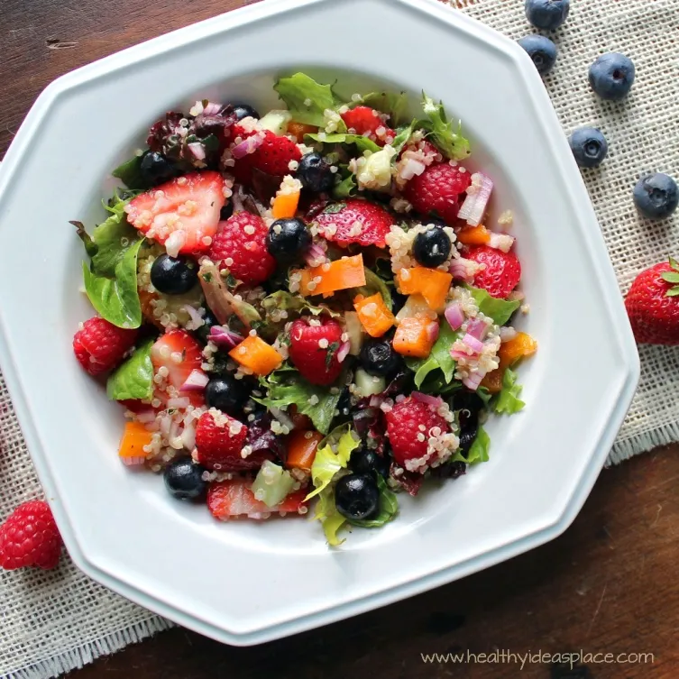 Triple Berry and Quinoa Salad with Mixed Greens places sweet berries and nutty quinoa amidst a backdrop of earthy mixed greens, cucumbers, and peppers, all pulled together with a balsamic vinaigrette for a colorful and scrumptious salad.