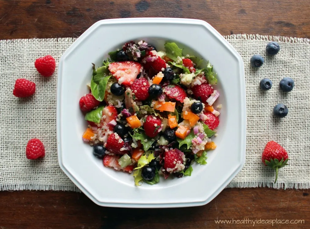 Triple Berry and Quinoa Salad with Mixed Greens places sweet berries and nutty quinoa amidst a backdrop of earthy mixed greens, cucumbers, and peppers, all pulled together with a balsamic vinaigrette for a colorful and scrumptious salad.