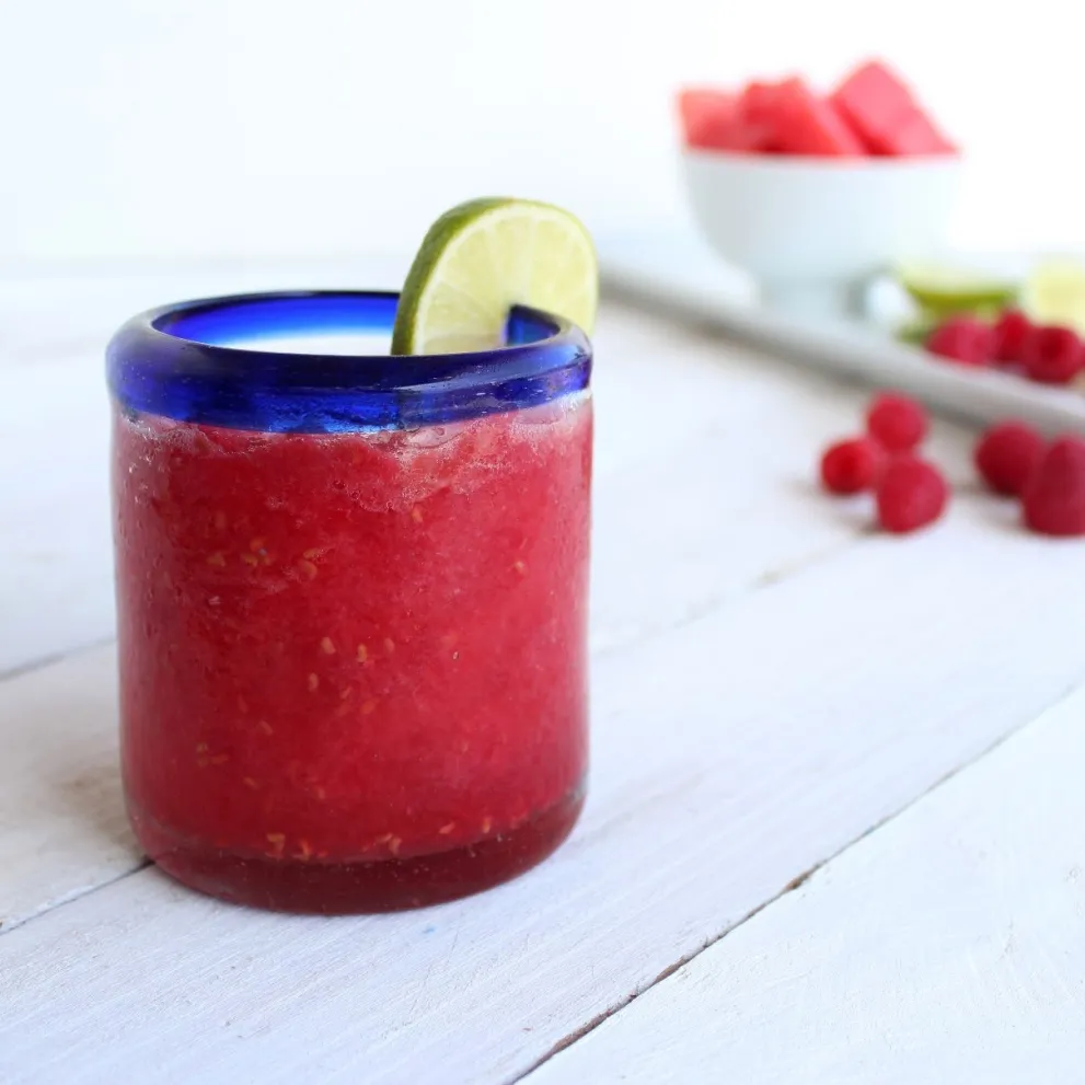 closeup of a Raspberry Watermelon Slushie in a clear glass with a blue rim