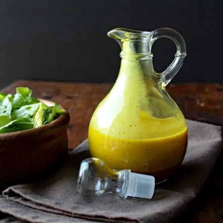 Apple Cider Turmeric Vinaigrette in a cruet on a dark towel