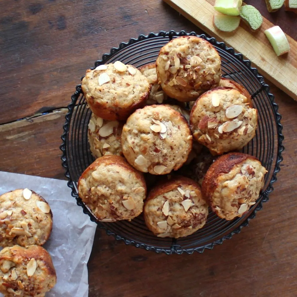 overhead photo of a bowl filled with Buttermilk Rhubarb Muffins and some rhubarb on the side