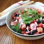 Watermelon, Blueberry, & Radish Salad in a serving bowl with a spoon and towel in the background