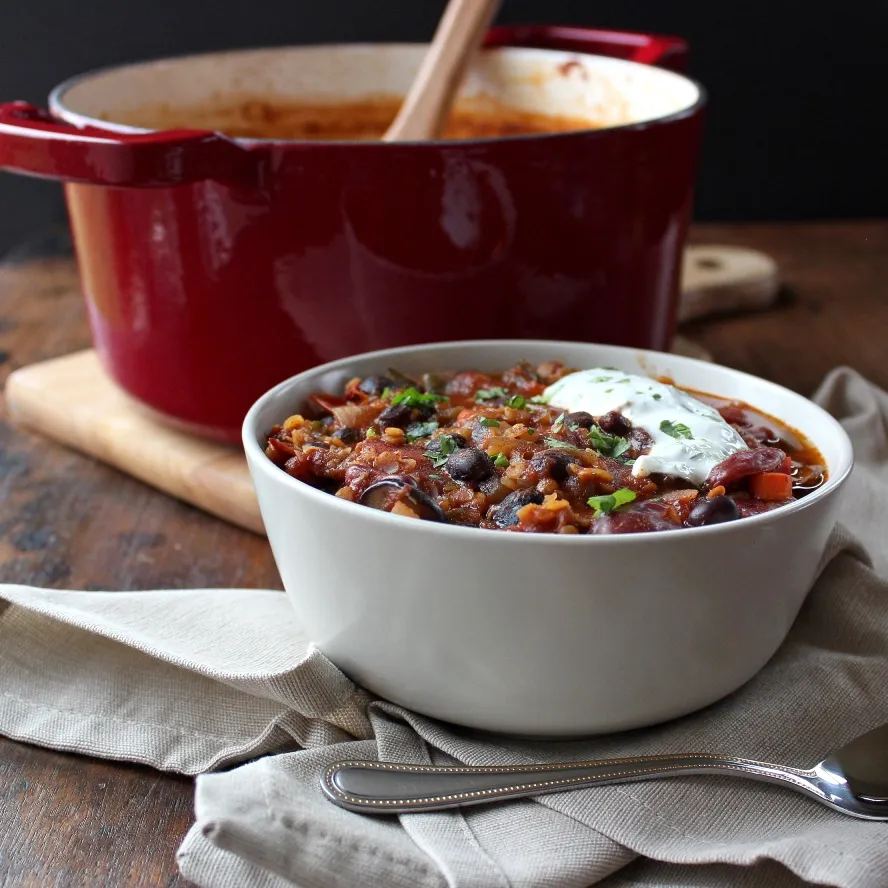 Vegetarian Chili with Red Lentils -in a white bowl with a napkin and spoon