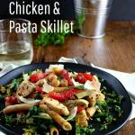 Herbed Chicken and Pasta on a black plate with a glass of wine