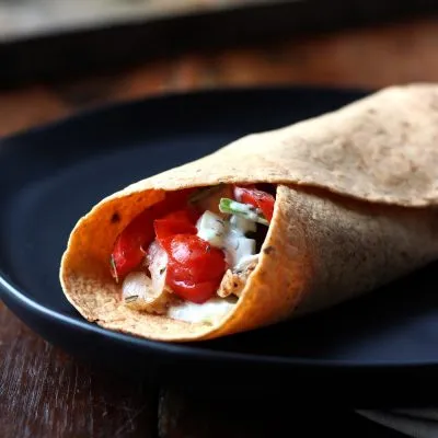 closeup of a Warm Tzatziki Chicken Wrap on a black plate