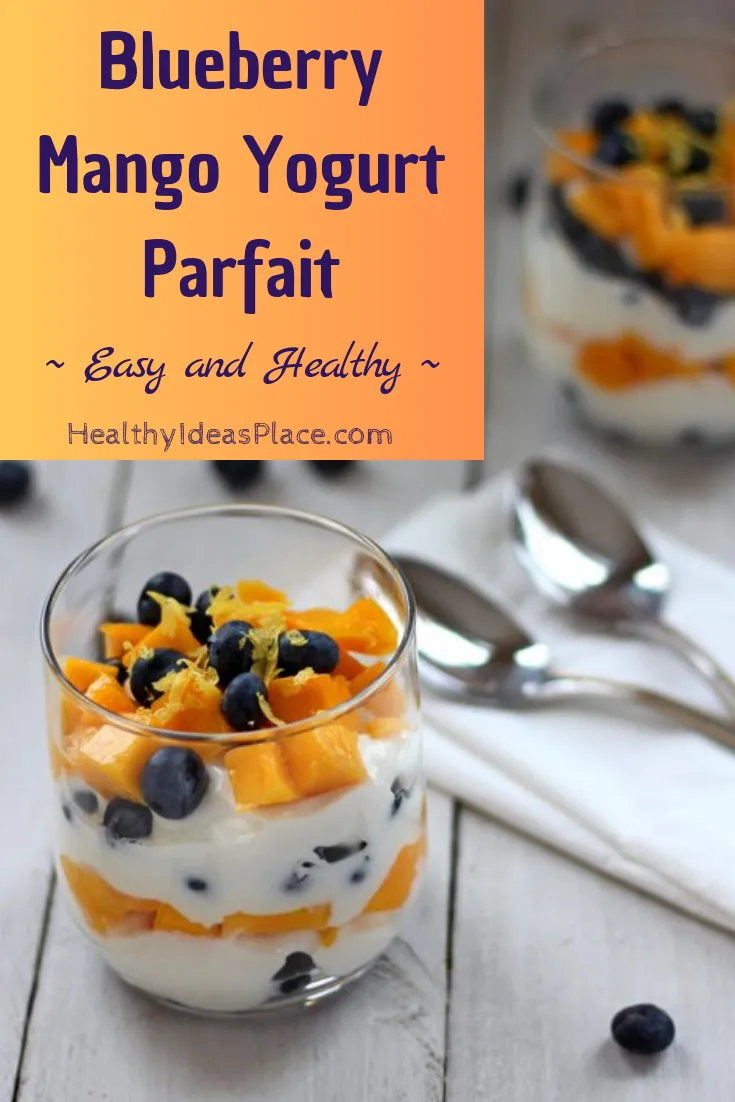 Diced mango and fresh blueberries layered with Greek yogurt in a clear glass