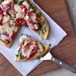 Roasted Red Pepper Chicken and Spinach Naan Pizza close up cut on cutting board
