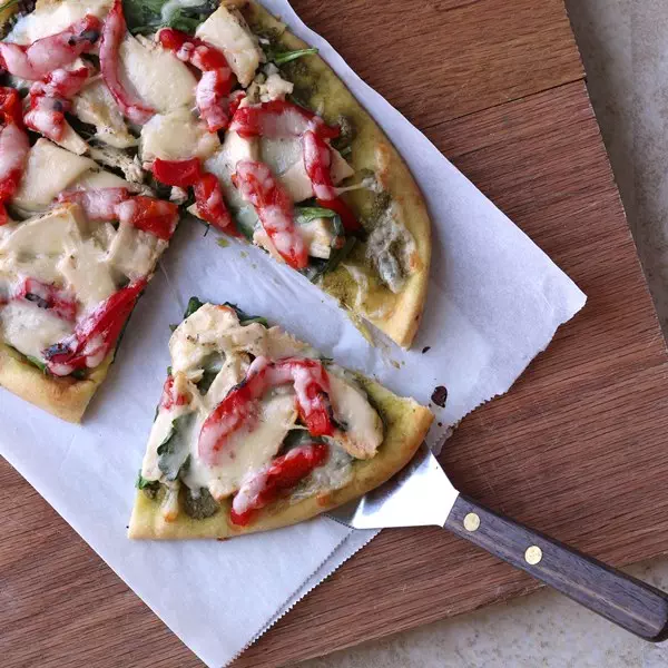 Roasted Red Pepper Chicken and Spinach Naan Pizza close up cut on cutting board