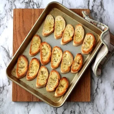 Toasted crostini on pan sitting on cutting board