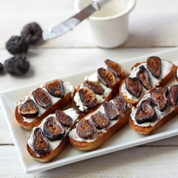 crostini with ricotta cheese and sliced figs on white plate