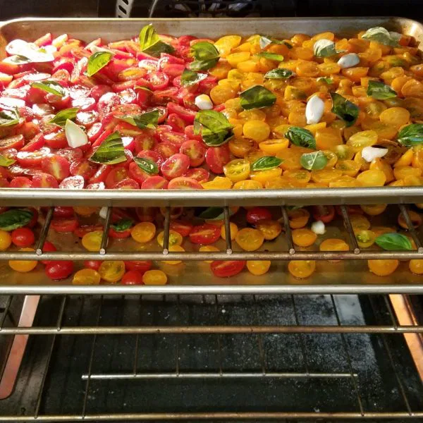 Two pans of grape tomatoes in an oven
