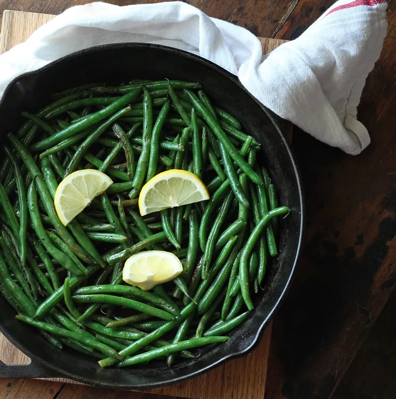 Green beans in dark skillet with lemon slices