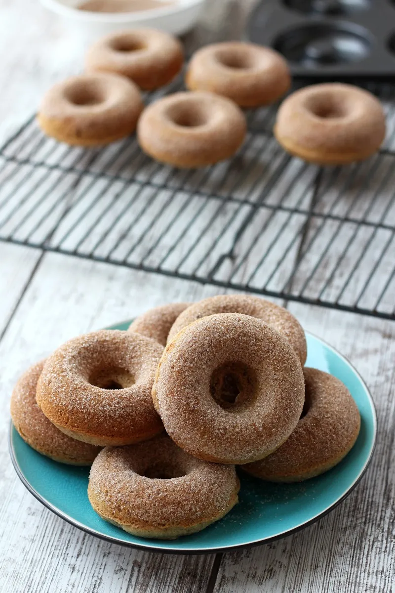 donuts on teal plate with donuts on cooling rack in background