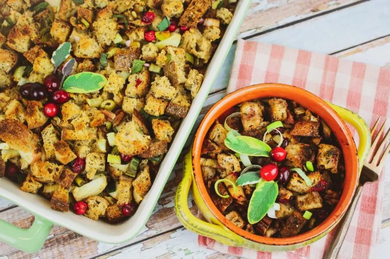Whole grain stuffing in white pan beside stuffing in orange bowl