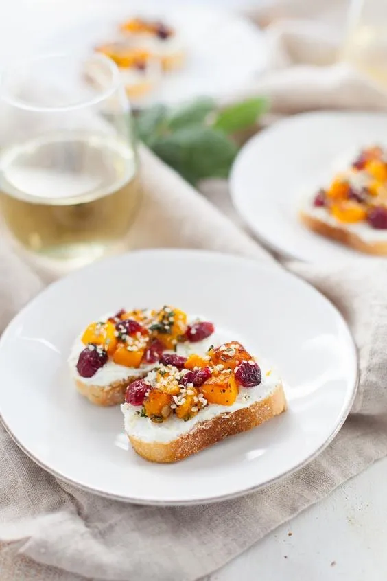 crostini topped with cranberries on white plate