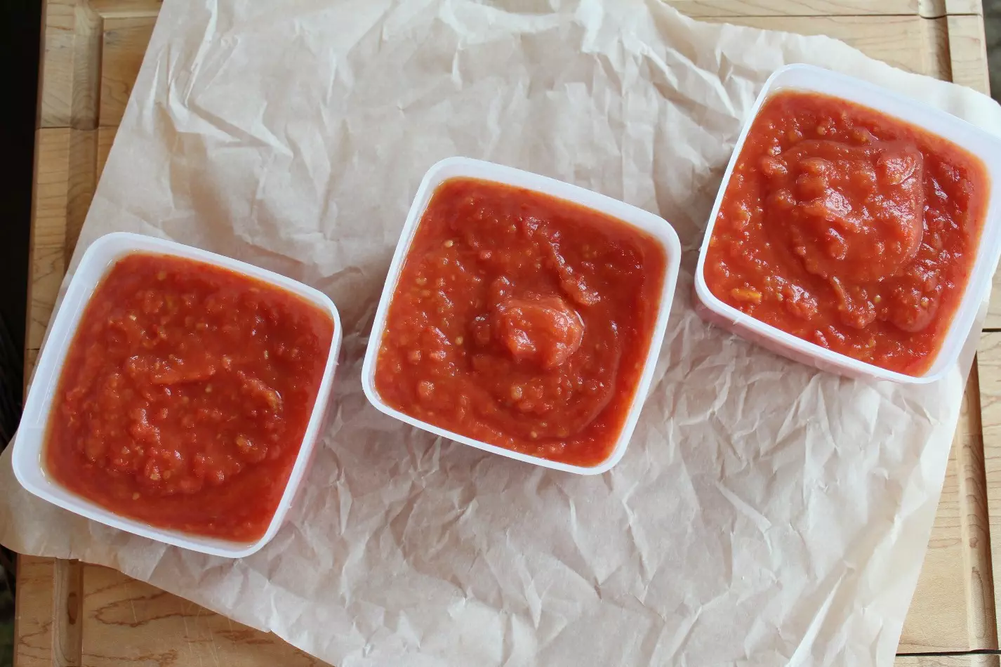 Three containers of tomato sauce on white background