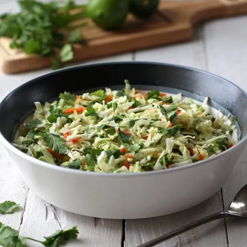 Coleslaw in a white serving bowl on a white background