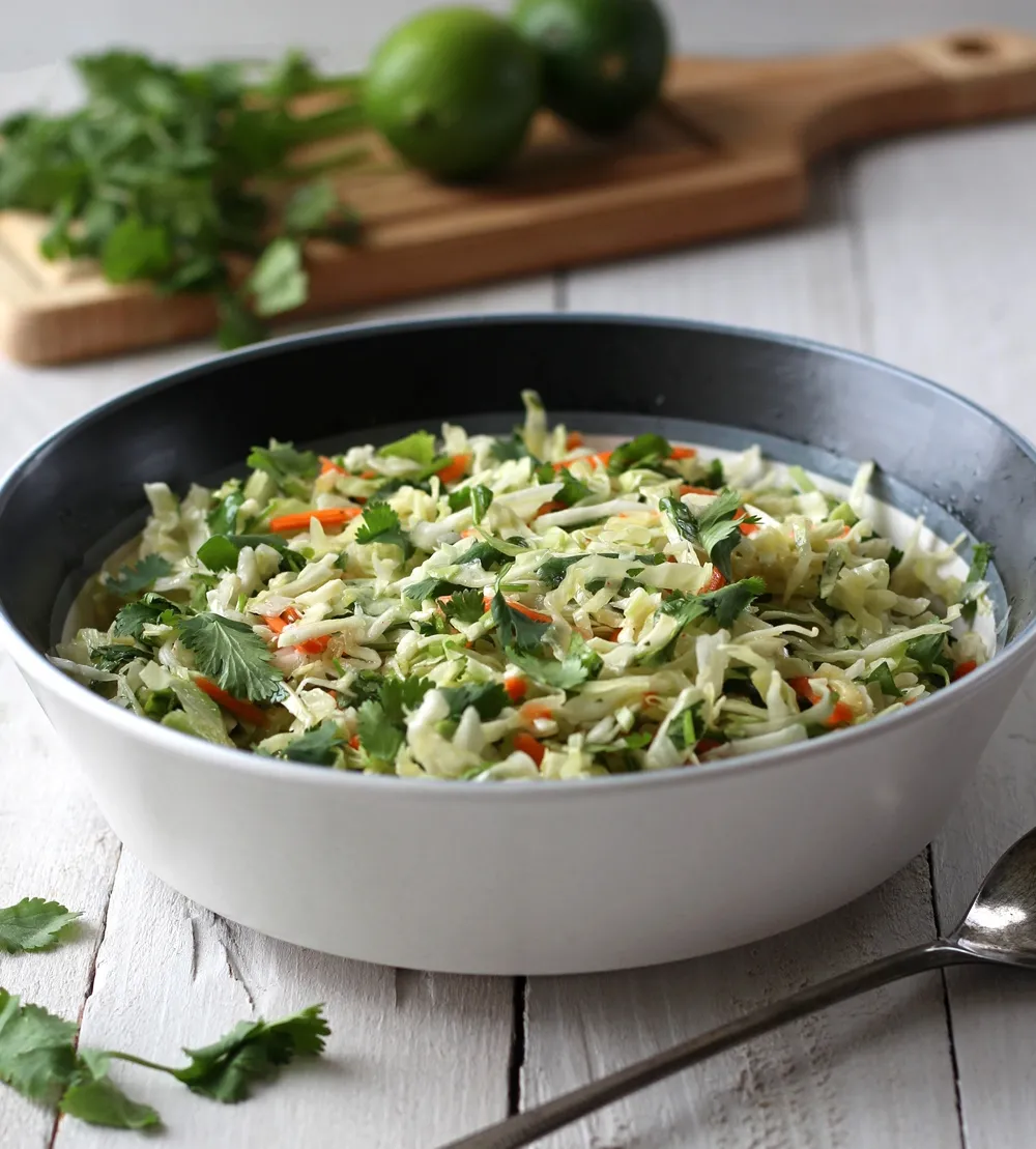 Coleslaw in a white serving bowl on a white background