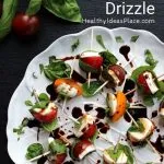 fresh basil leaves wrapped around cherry tomatoes and mozzarella on white plate