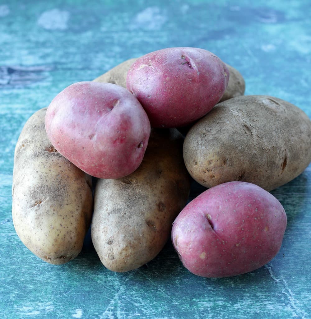 unpeeled raw potatoes on green surface