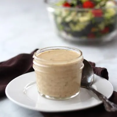 salad dressing in clear jar with salad in the background