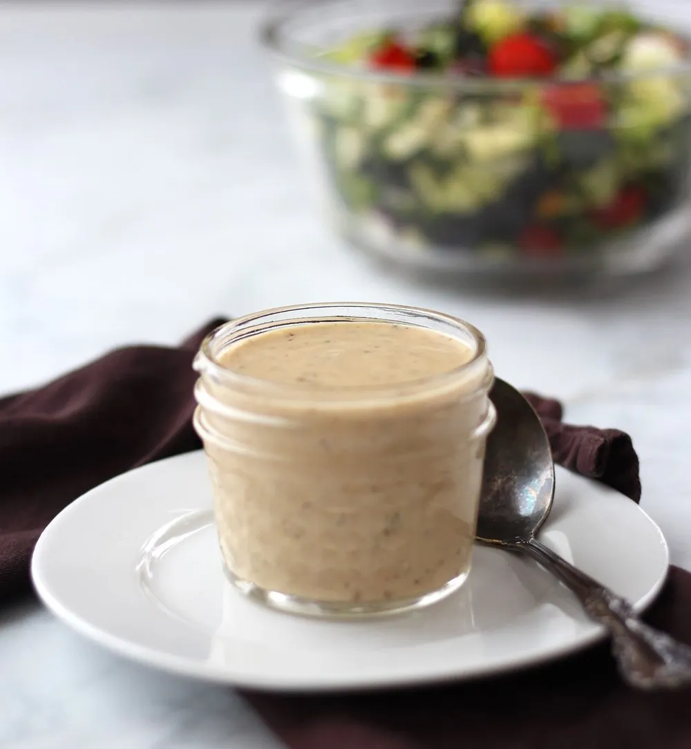 salad dressing in clear jar with salad in the background