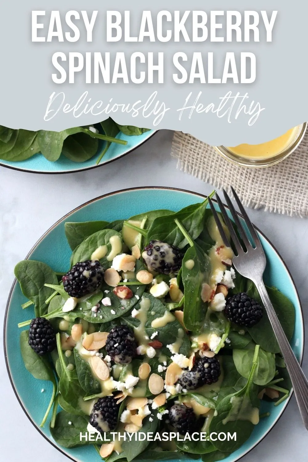 Spinach salad with blackberries, feta cheese, sliced almonds and dressing on a teal plate, looking down on it from above