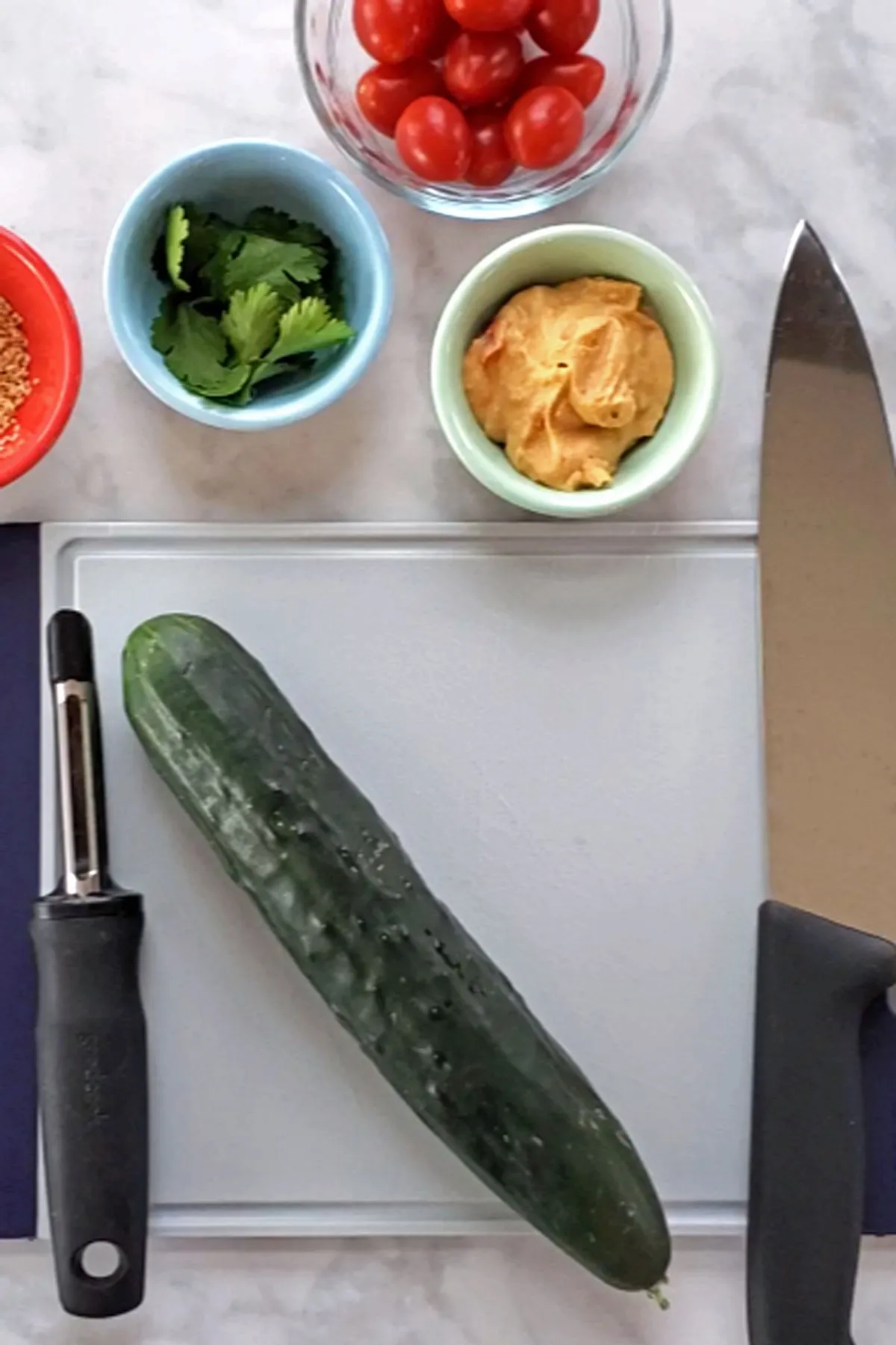 Ingredients for cucumber and hummus appetizer against a white background
