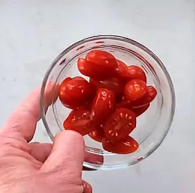 Sliced grape tomatos in a glass bowl