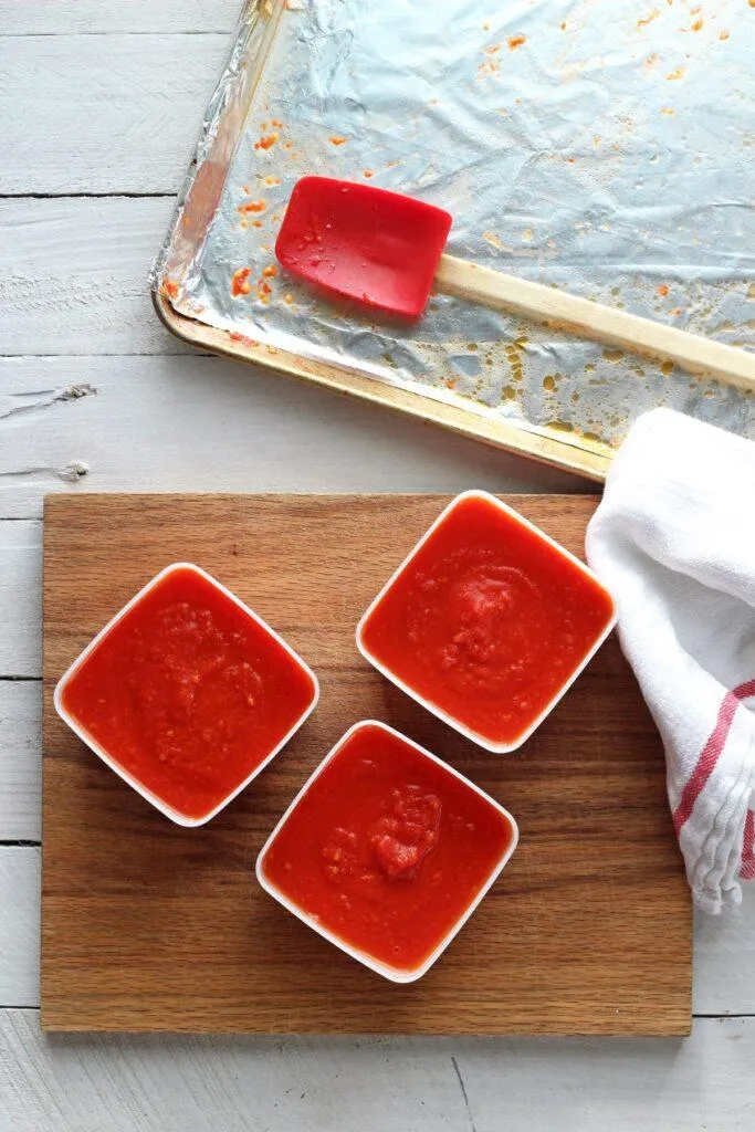 Tomato sauce in freezer containers on wooden cutting board