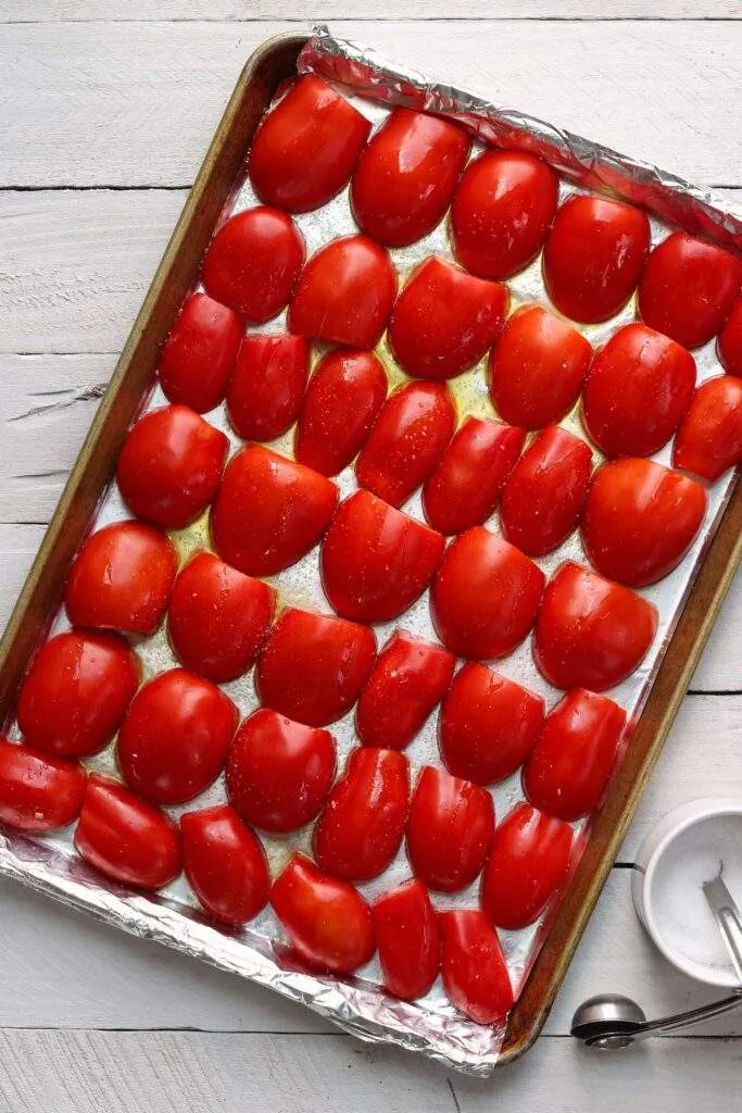 Halved tomatoes on pan with oil and salt