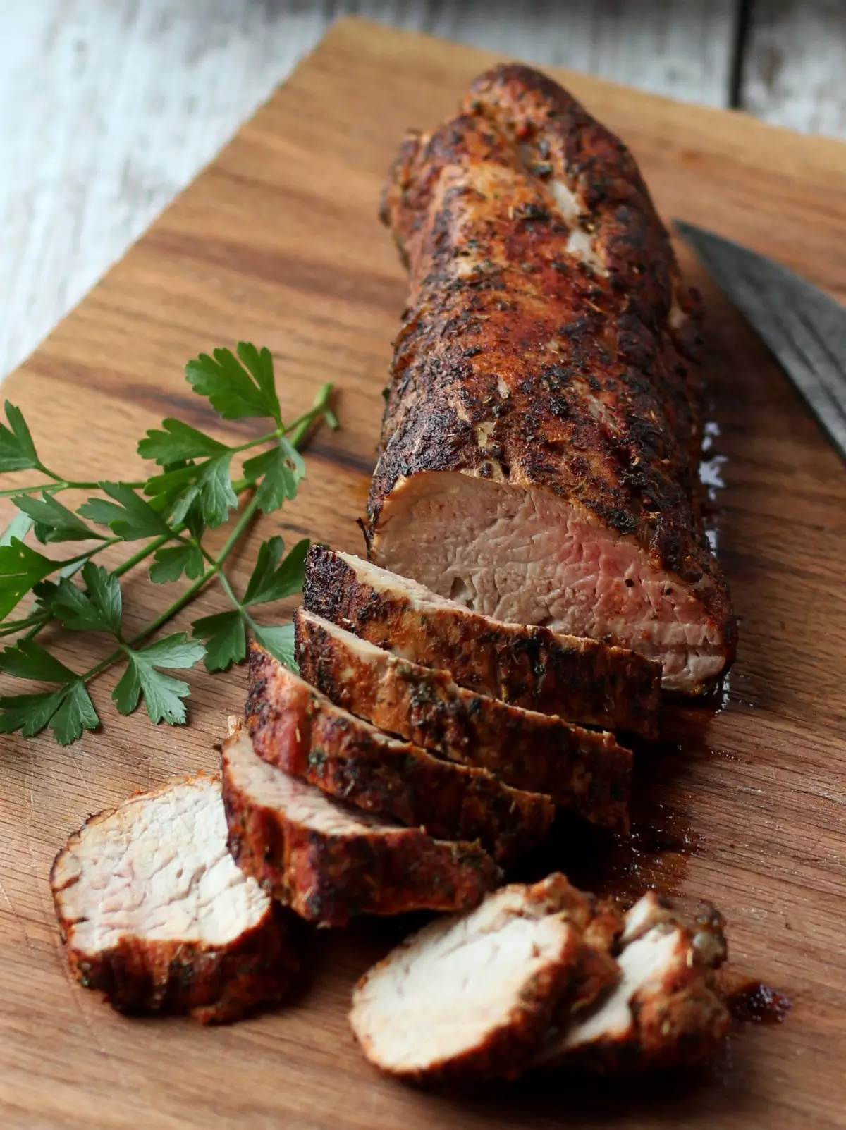 Sliced cooked pork tenderloin on wood cutting board
