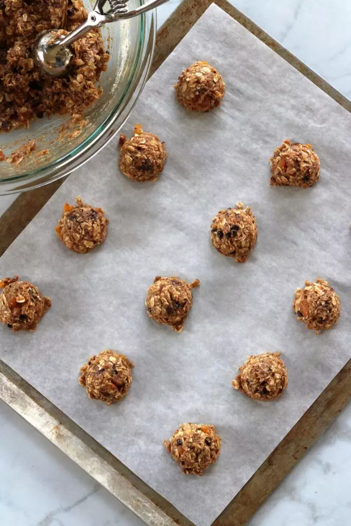 balls of raw breakfast cookie dough on parchment paper lined pan.