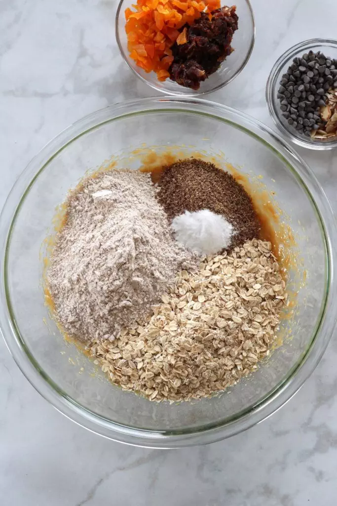 Clear bowl holding wet and dry ingredients for oatmeal breakfast cookies